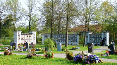 Foto von der Ferne auf die drei Urnenmauern auf dem Friedhof Kaufering West